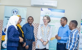 Six people stand inside a room in a semi-circle smiling and laughing.