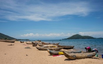 Women reach into boats on a beach in Malawi. 