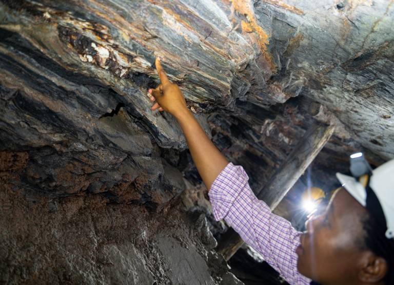 A woman points out something of interest inside a small-scale mine.