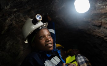 A miner looks up toward a light in a mining tunnel in Rwanda. Credit: Brian Clark/Pact.