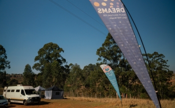 A van parked outside on a dirt area with a sign that reads DREAMS.