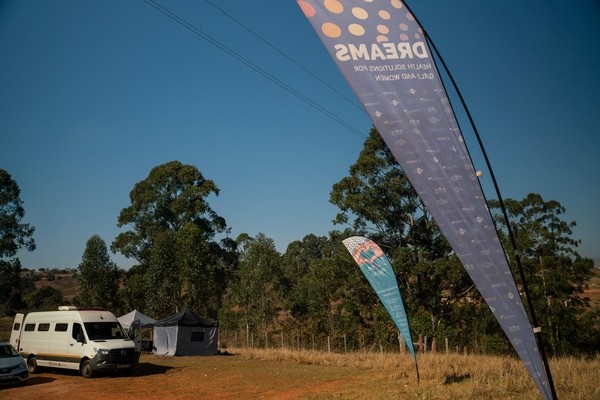 A van parked outside on a dirt area with a sign that reads DREAMS.