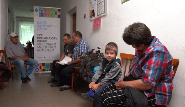 A young boy waits to see a doctor from the mobile health team, which brings essential health care services directly to remote communities. Photo credit: Pact.